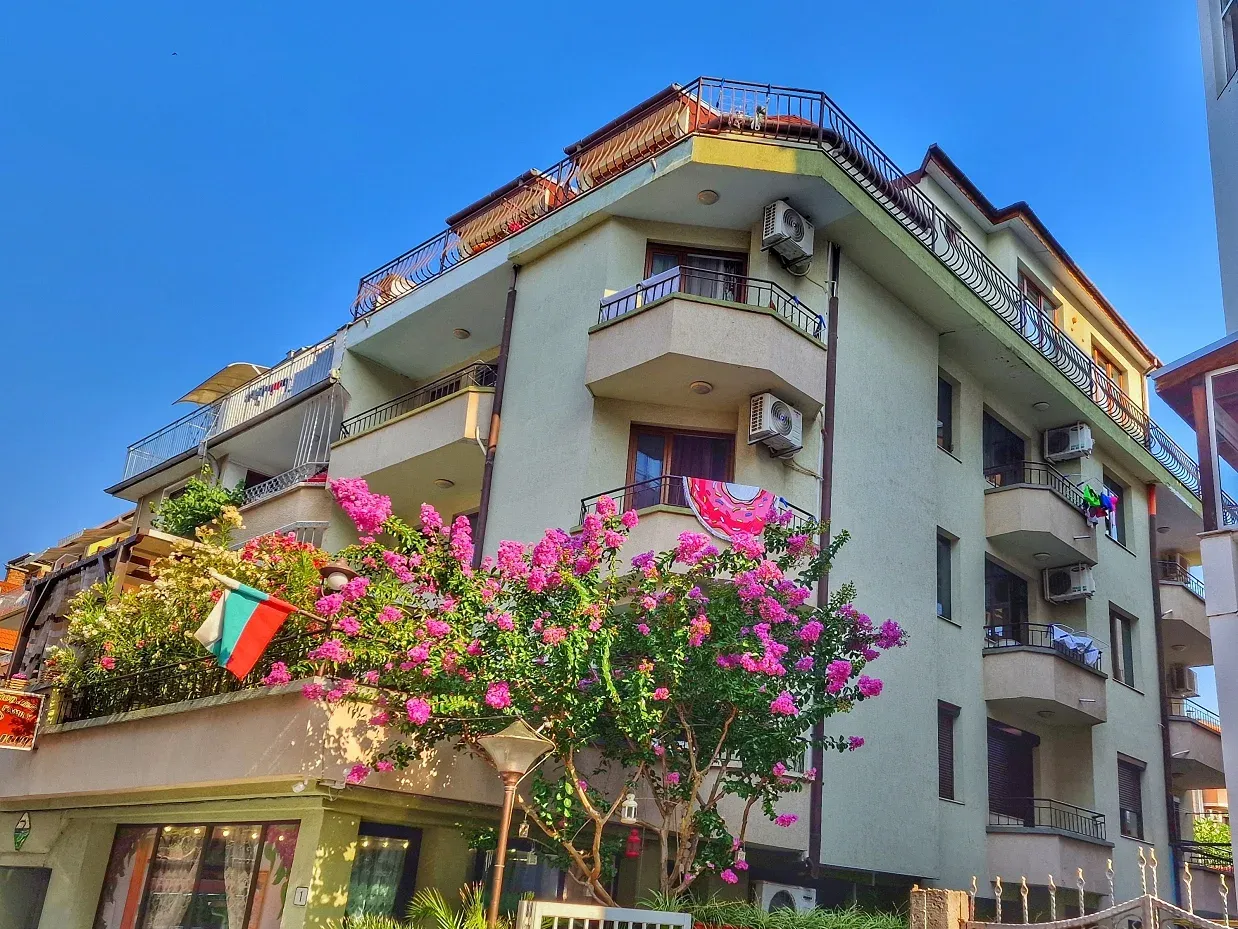 Clădire colorată cu balcoane și flori în față. - Clădire colorată cu balcoane și flori în față.