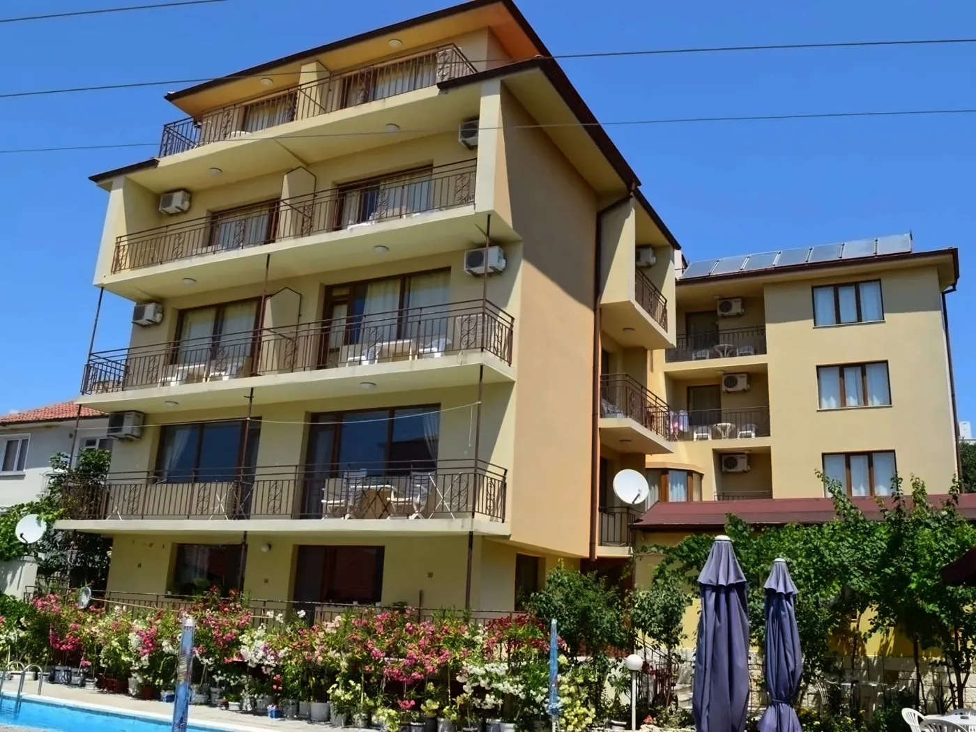 Vedere exterioară a unui hotel cu patru etaje, cu balcoane și grădini de flori. - Vedere exterioară a unui hotel cu patru etaje, cu balcoane și grădini de flori.