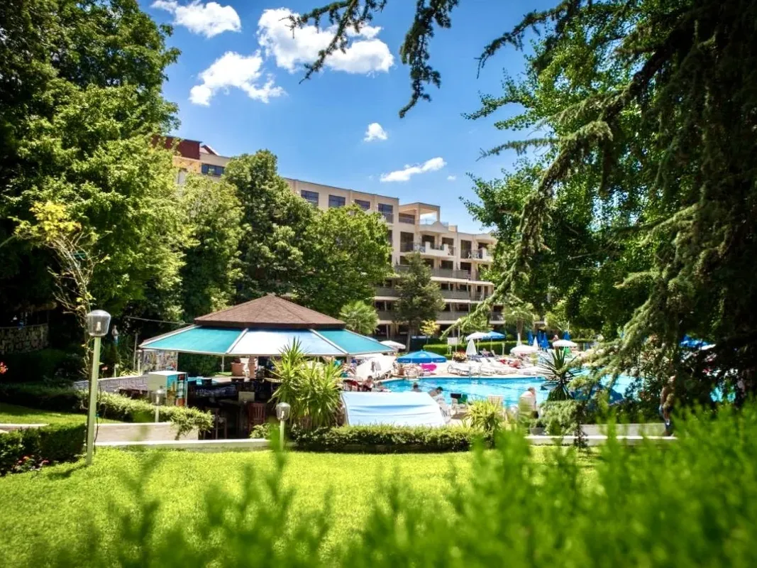 Vedere asupra zonei piscinei hotelului înconjurată de verdeață și cer albastru. - Vedere asupra zonei piscinei hotelului înconjurată de verdeață și cer albastru.